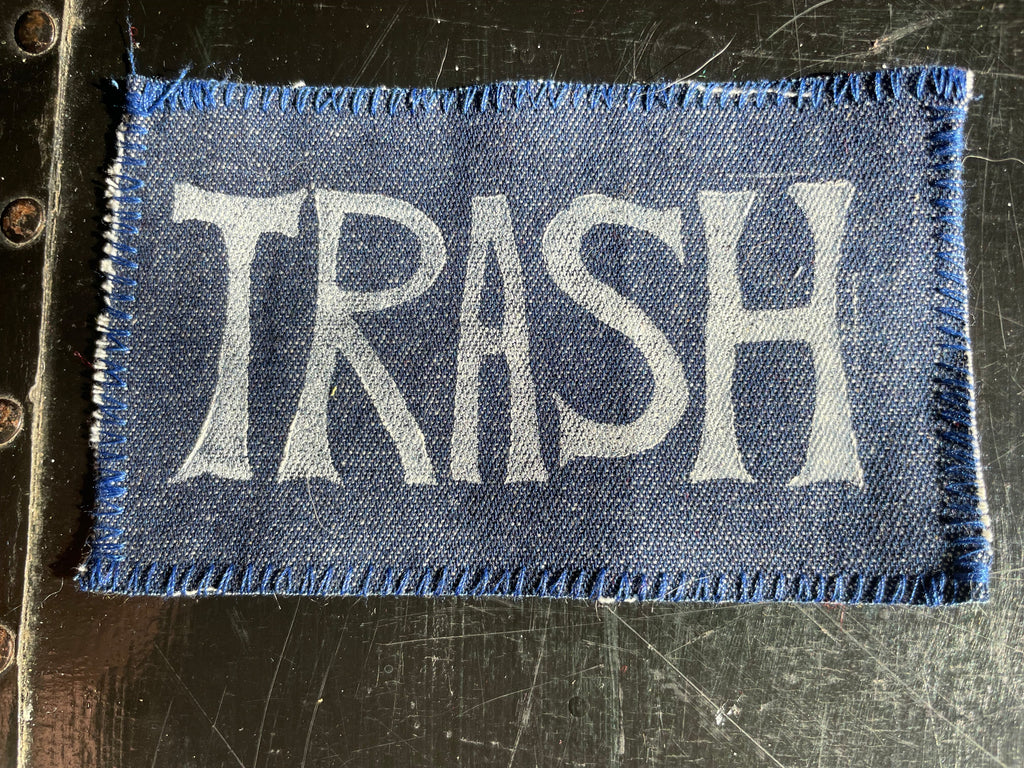 Denim patch with 'TRASH' text on a textured surface