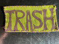Fabric patch with 'TRASH' text on a green background