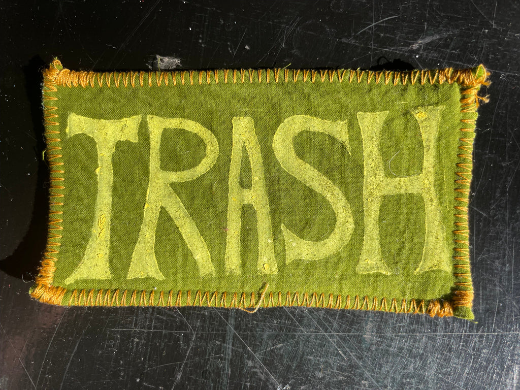 Green patch with 'TRASH' text on a dark textured background