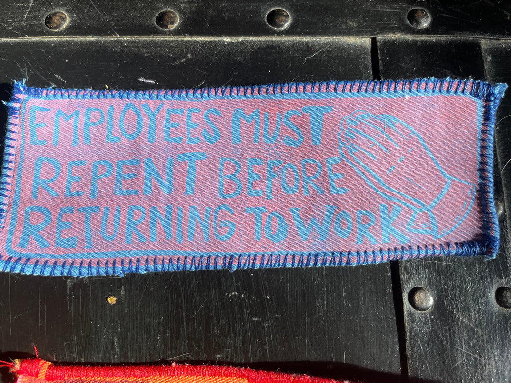 Pink patch with blue text and graphics on a black background